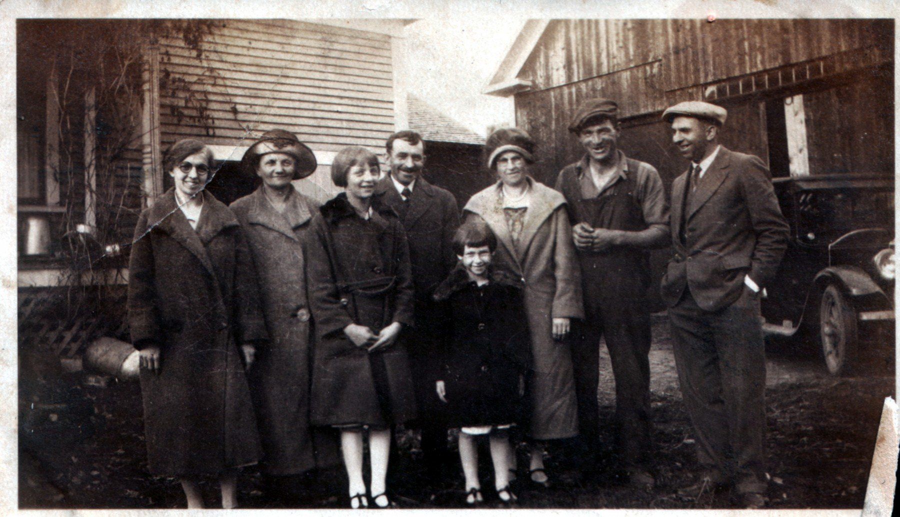 family portrait at Isham Family Farm in Vermont, with three generations standing in front of the farmhouse and barn.