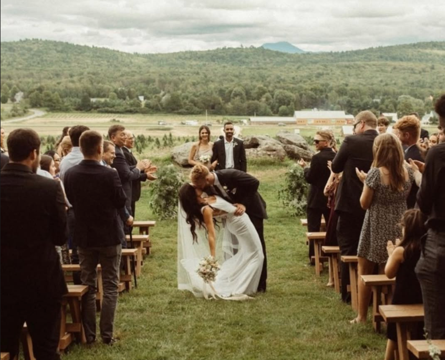 newlywed couple kissing after getting married at isham family farm with the vermont mountainside in the background