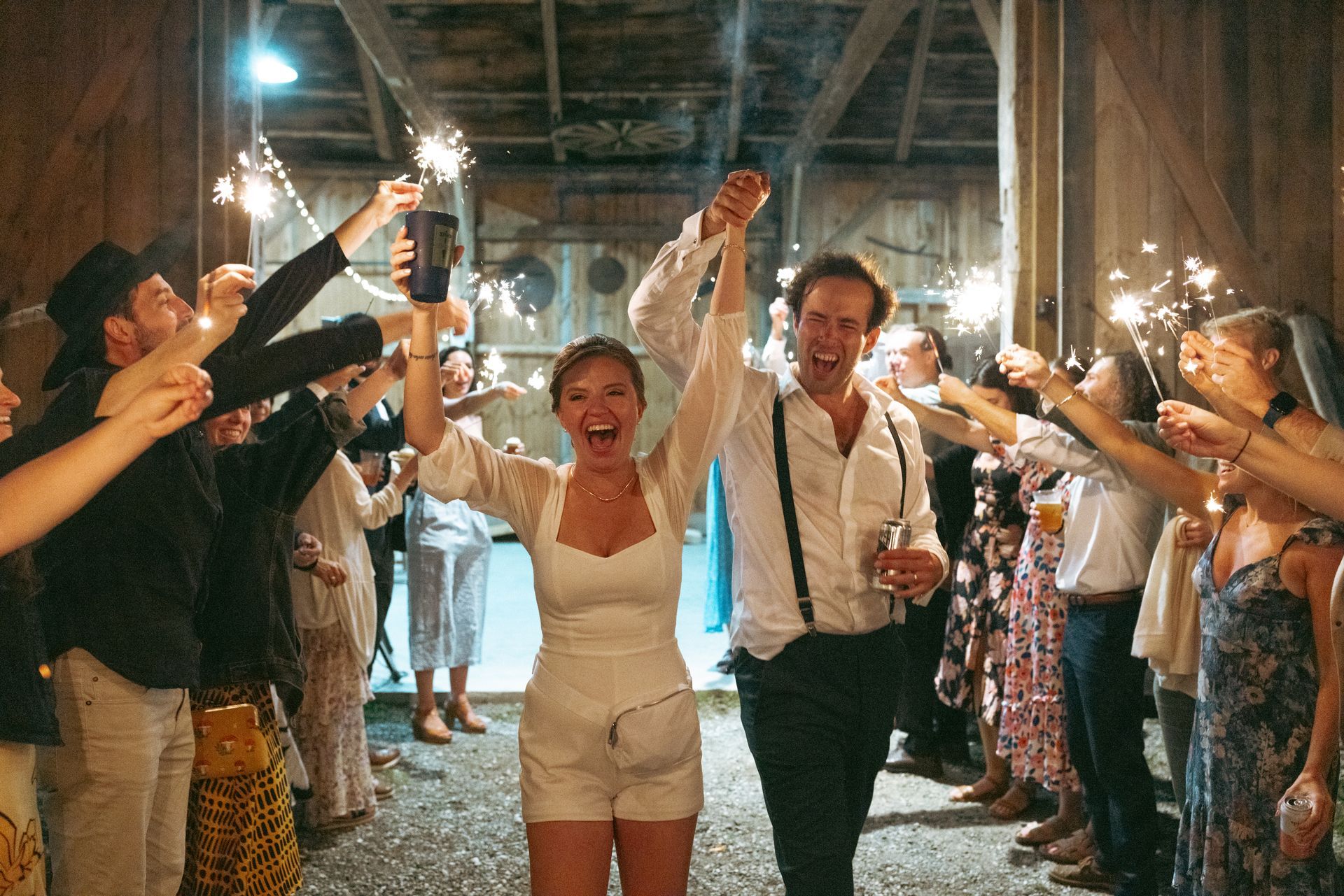 bride and groom walking out of their reception through a tunnel of sparklers held by friends and family at isham family farm