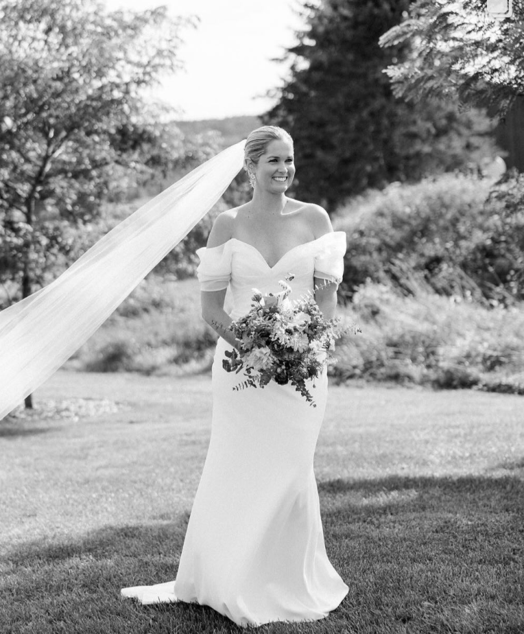smiling bride on her wedding day at isham family farm with her veil blowing in the wind