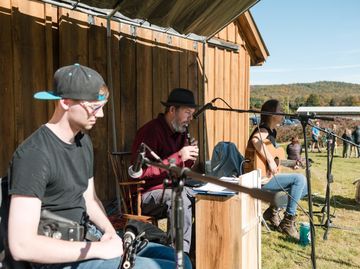 Live folk music at Isham Family Farm event with musicians performing beside the barn in autumn.