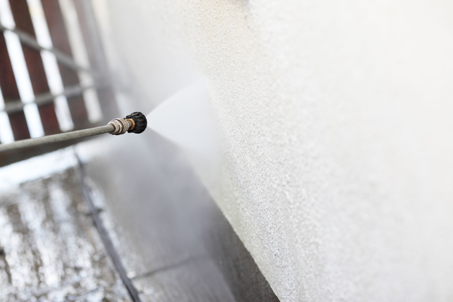A person is using a high pressure washer to clean a wall.