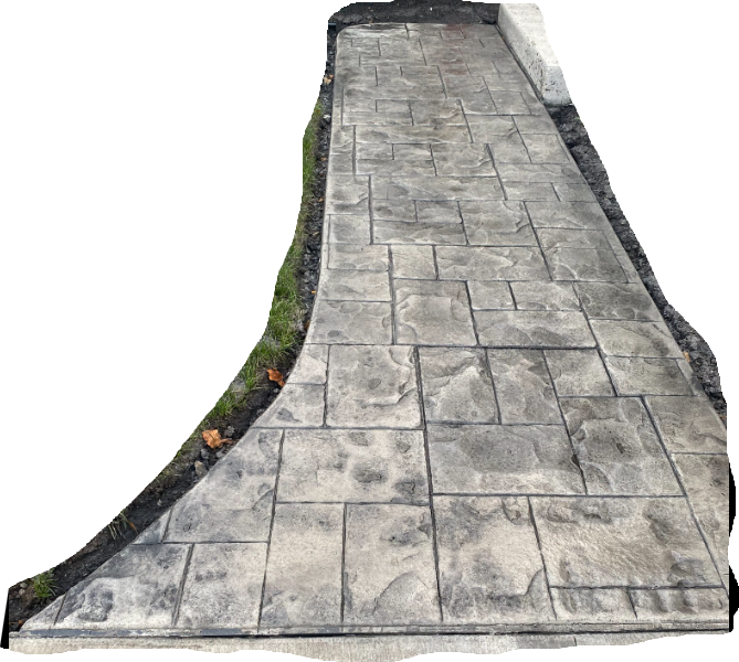 A walkway made of gray, rectangular stamped concrete tiles, with an curved edge bordered by grass and dark soil.