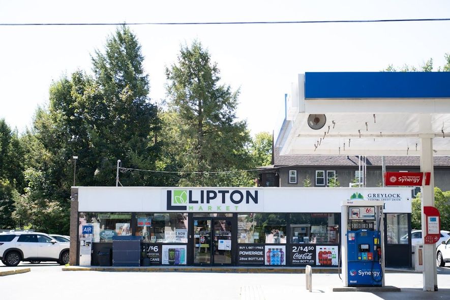 Lipton Market convenience store with gas pumps under a white canopy, sunny day.
