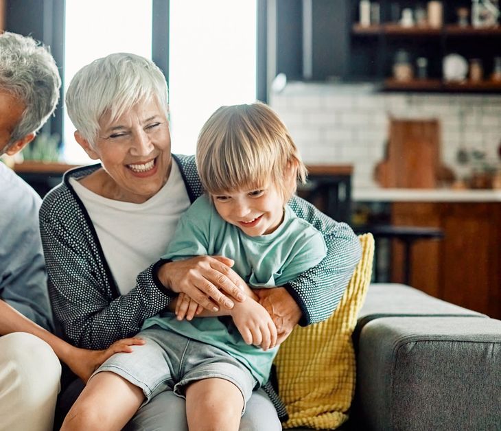 Smiling older woman hugging a child on a sofa in a cozy living room