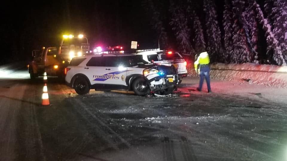 Police SUV crashed on icy road at night, with emergency lights flashing and a responder standing nearby
