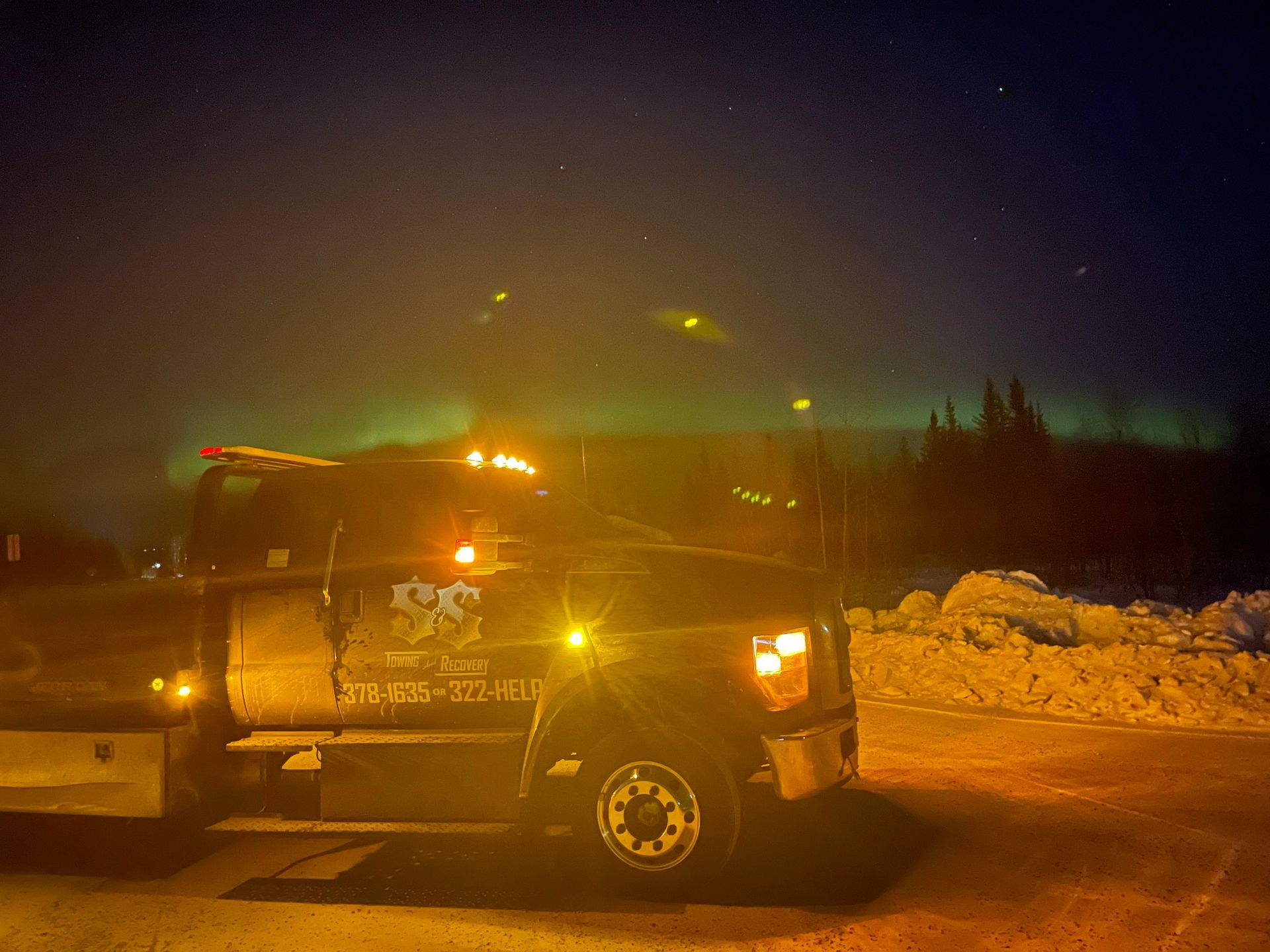 Snowplow with flashing lights on a snowy road at night