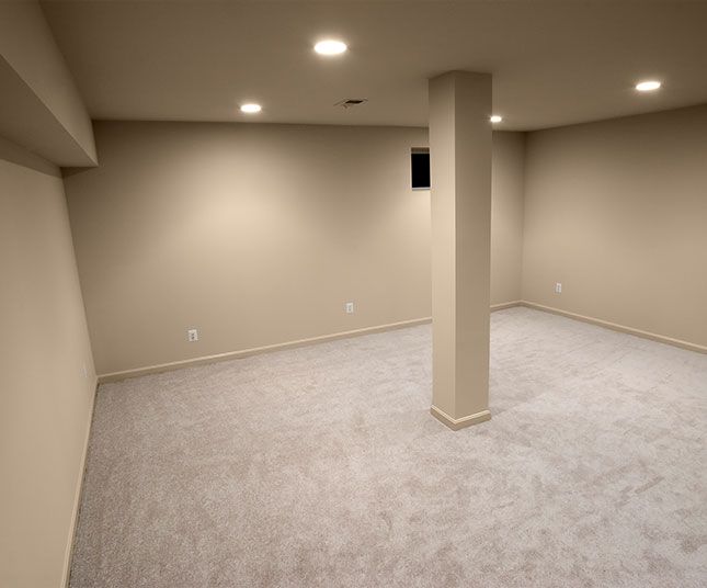 Empty beige carpeted basement room with recessed lights and a central support column