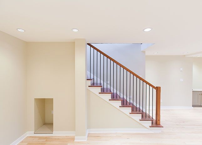 Bright modern stairwell with white walls, wooden handrail, and recessed lighting