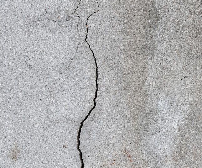 Cracked gray concrete wall with a vertical fissure running down the center