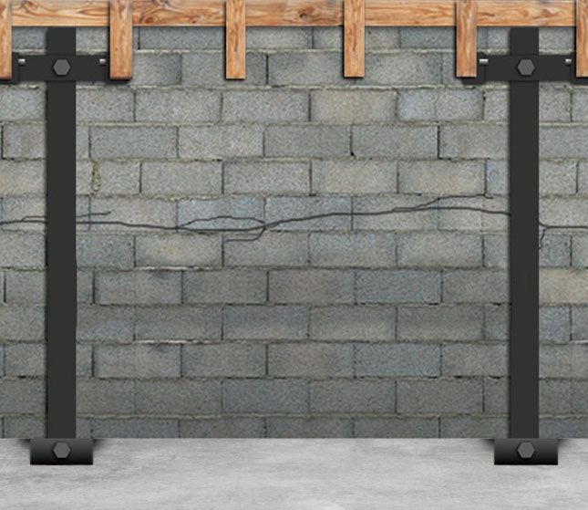 Gray cinder block wall with vertical black supports and wooden beam brackets at the top
