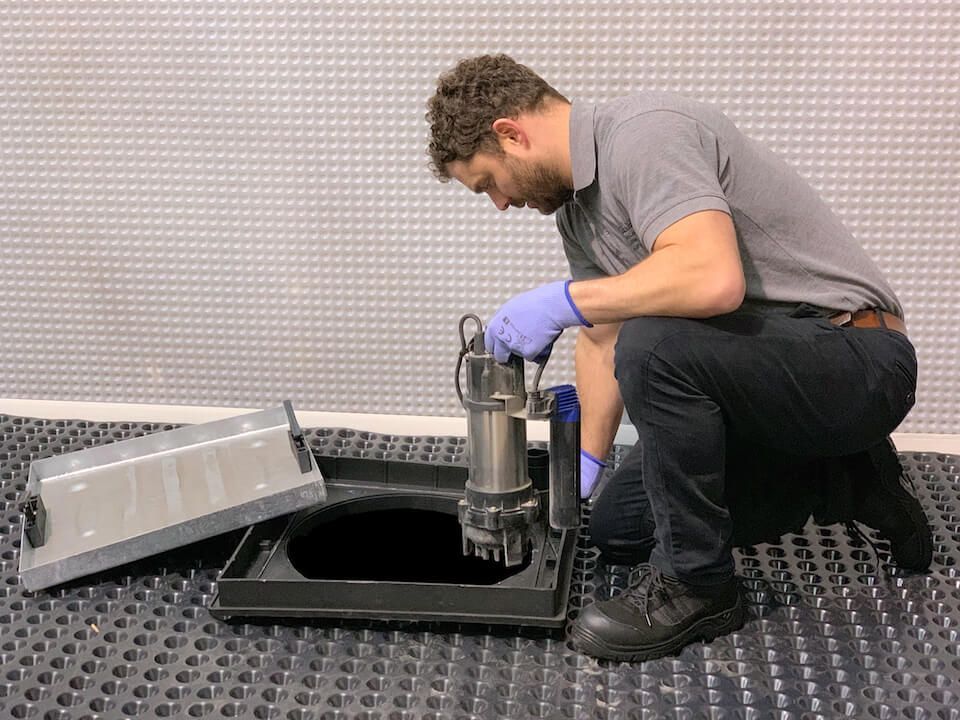 Professional technician installing a new sump pump and backup system