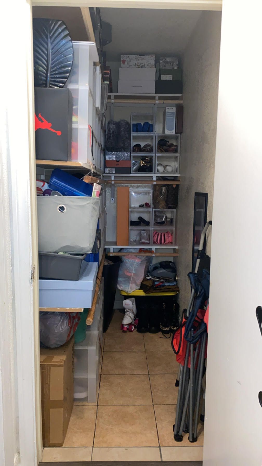 Narrow pantry hallway with shelves, boxes, and household storage items on both sides