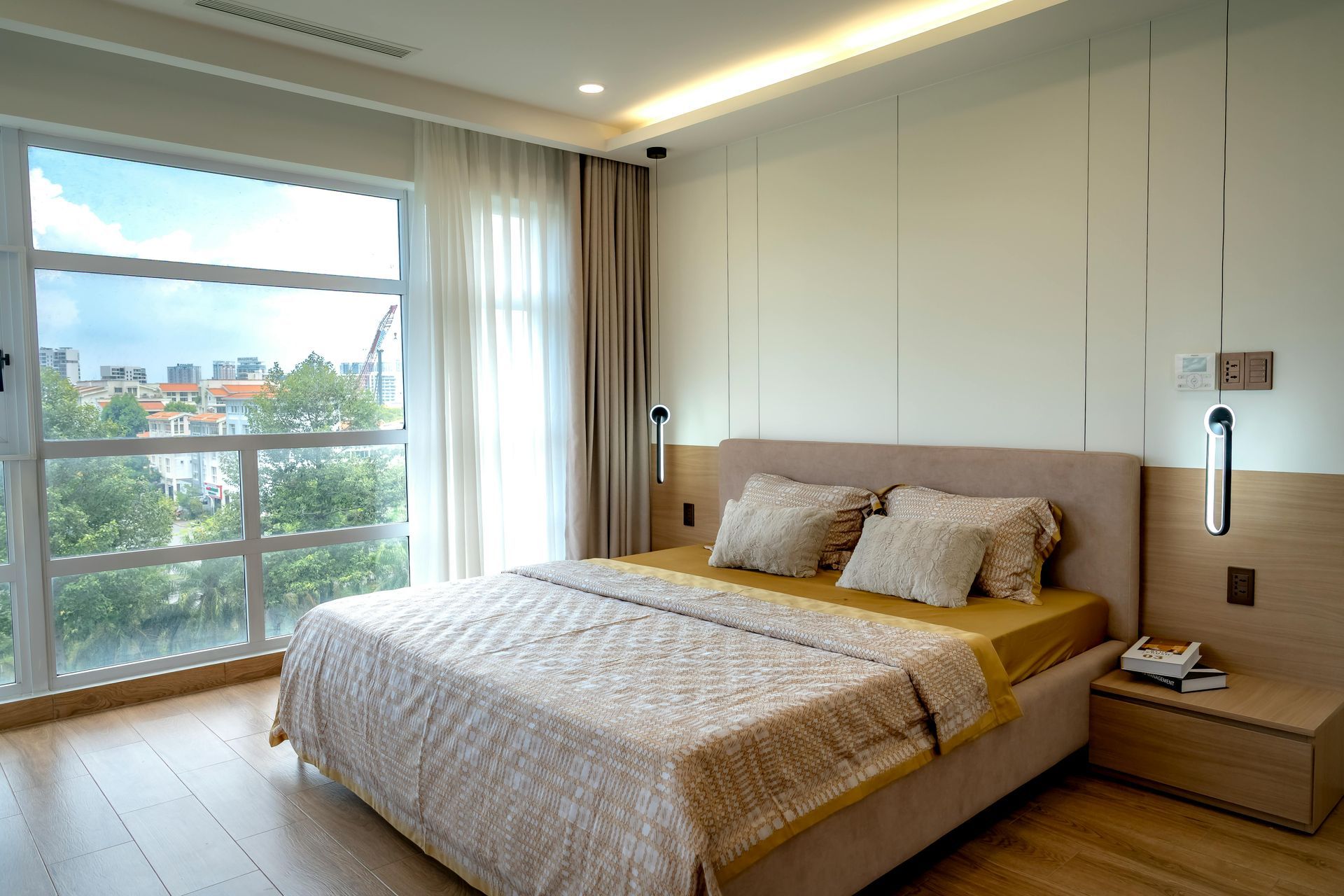 Modern bedroom with a large bed, floor-to-ceiling window, and city view