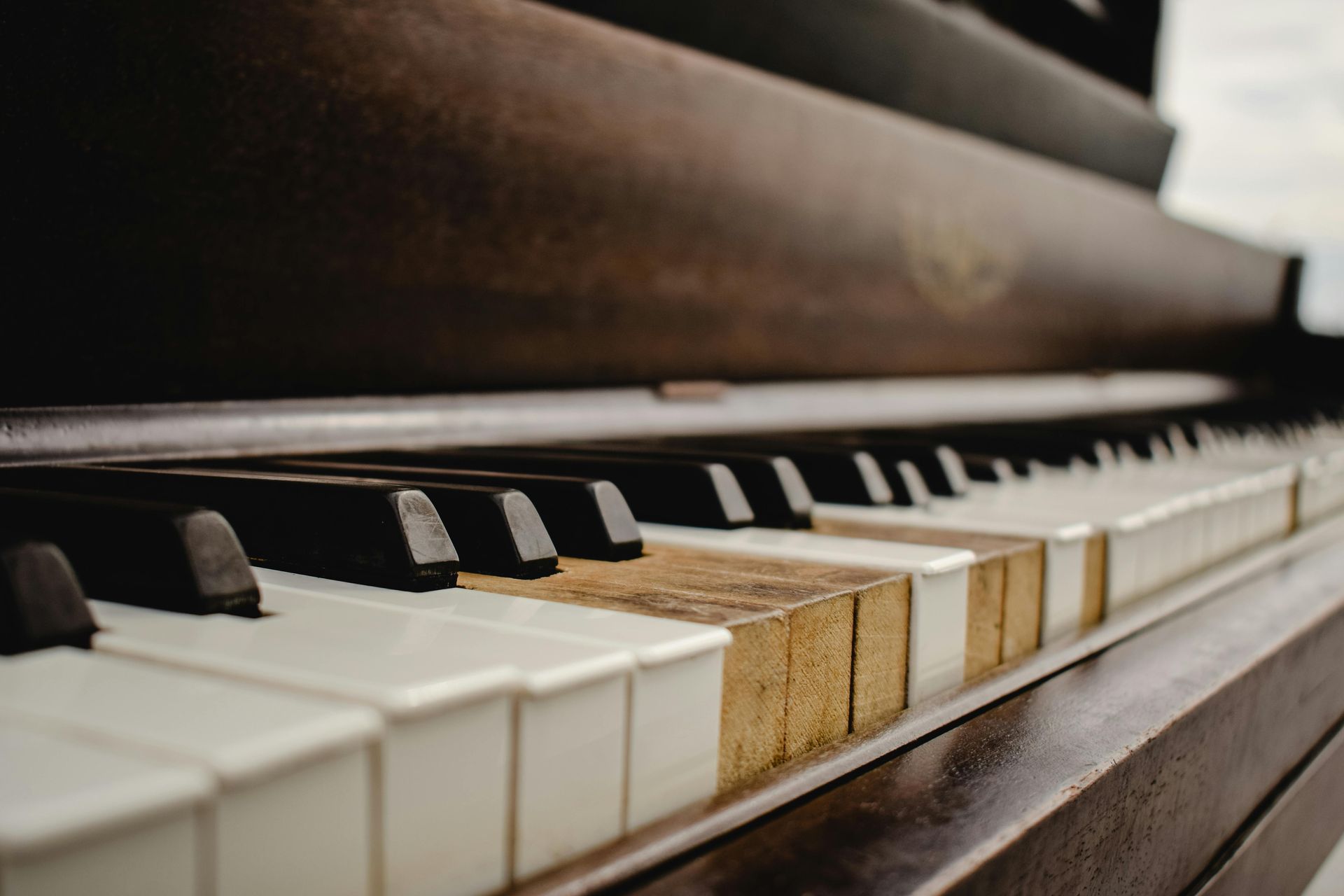 Close-up view of weathered piano keys, some missing their ivory covers, revealing the aged wood underneath.