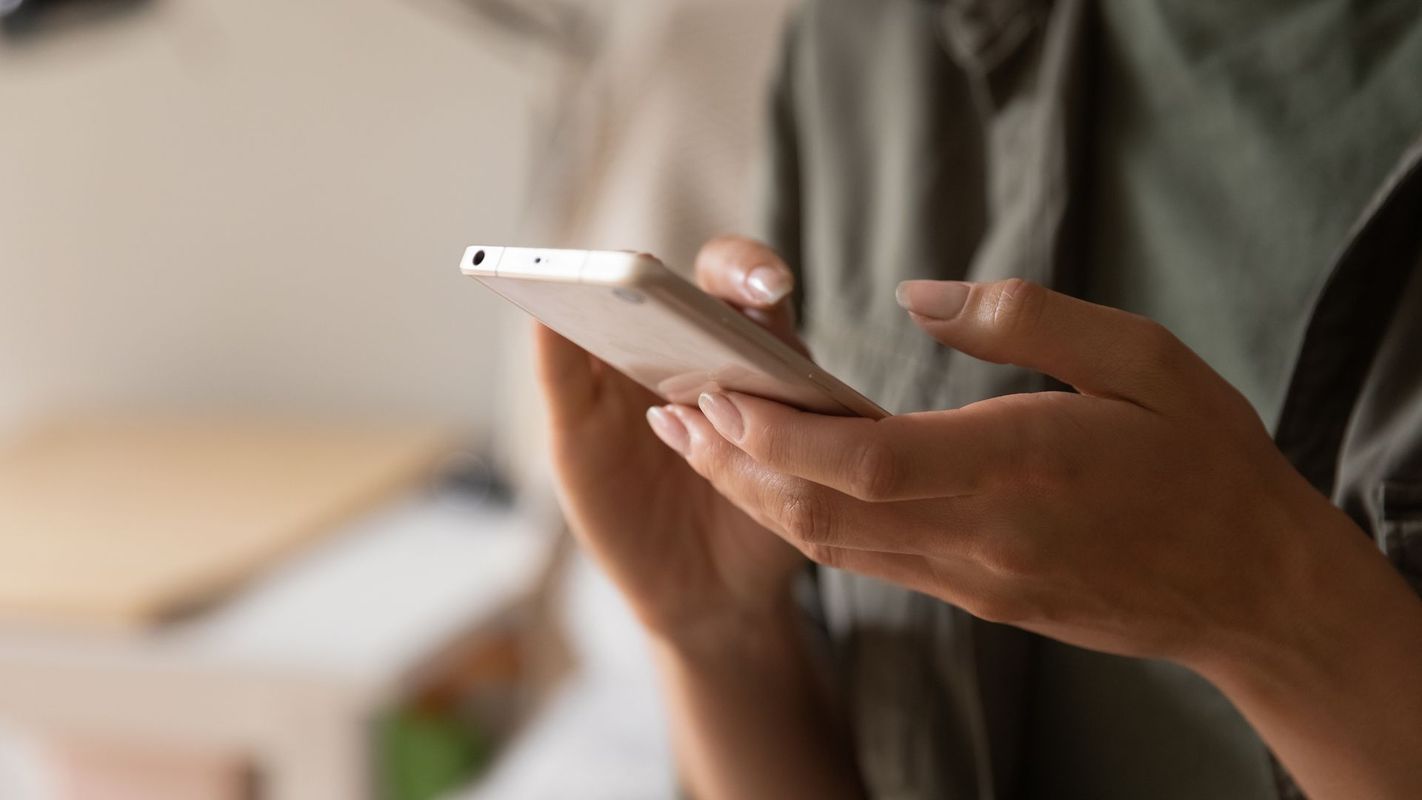 A woman is holding a cell phone in her hands.