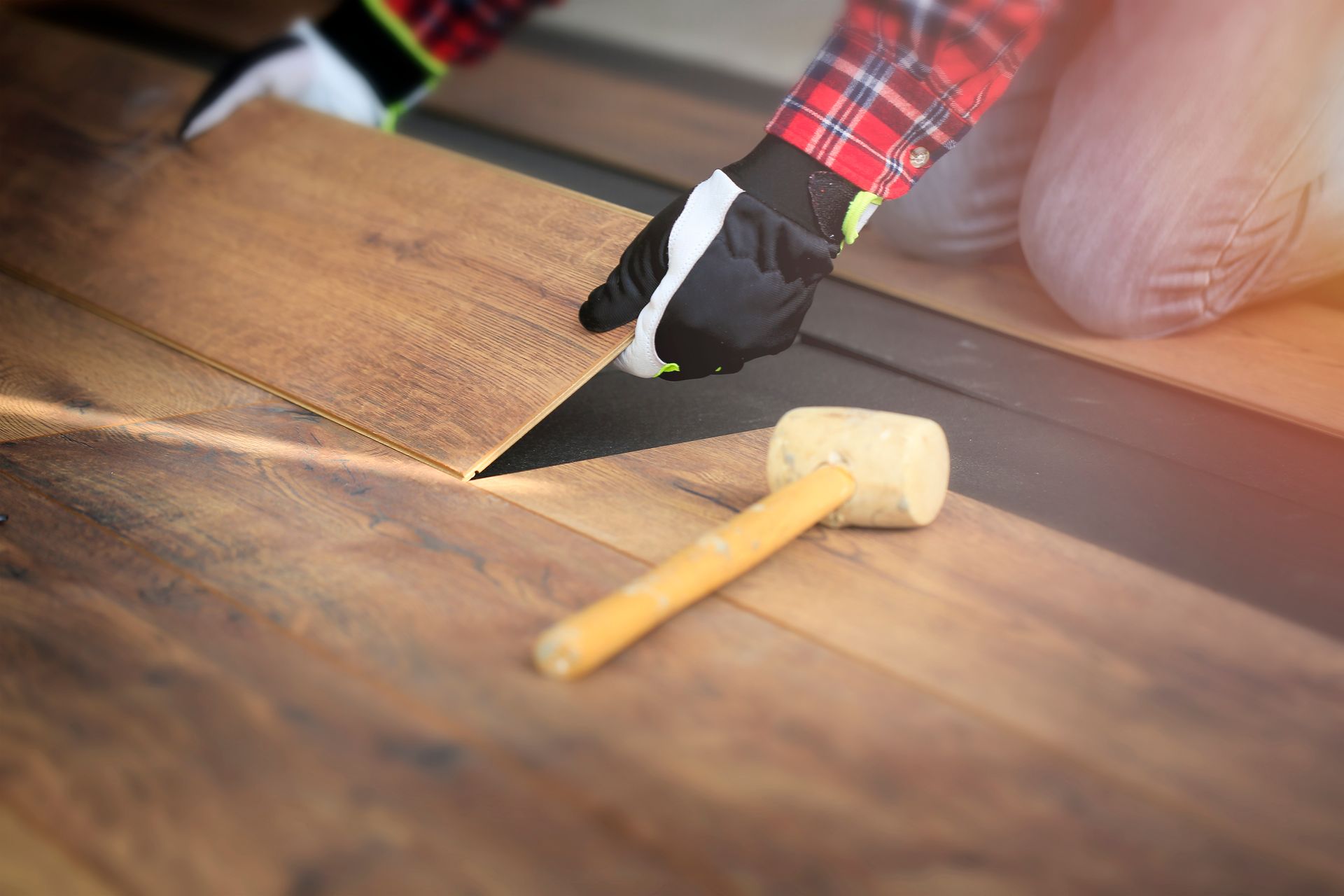 Worker installing timber look laminate flooring in a room. Worker installing timber look laminate flooring in a room.