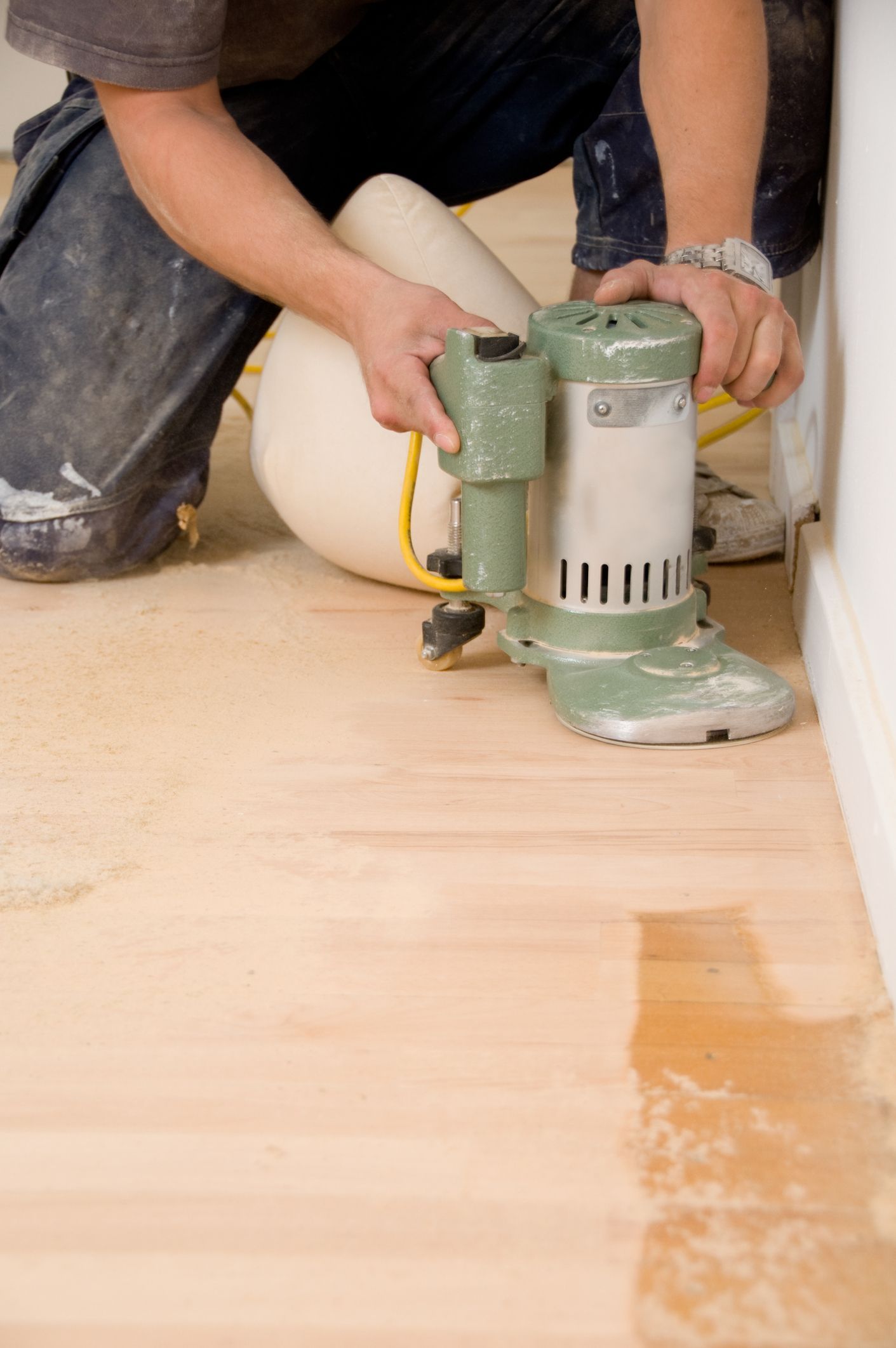 Professional hardwood flooring sanding with machine in home interior renovation project.