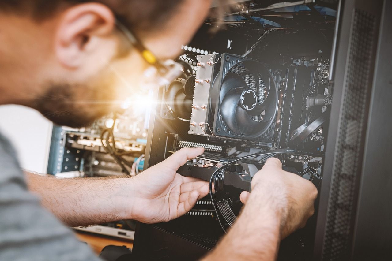 Man with glasses working inside a computer case, assembling or repairing components.
