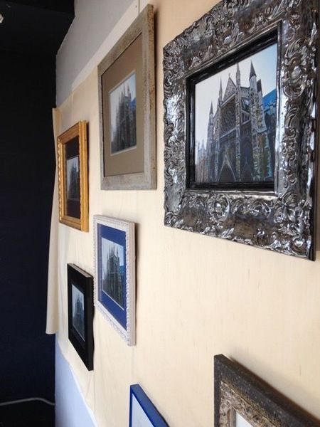 Framed cityscape photos arranged on a cream wall in a hallway
