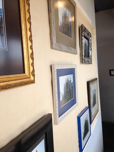Assorted framed pictures hanging on a beige wall in a hallway