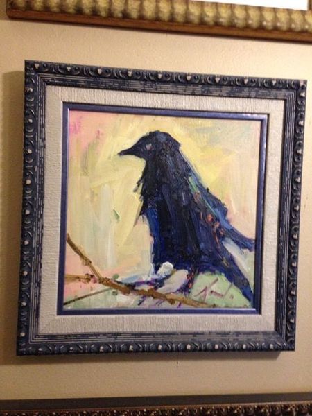 Framed painting of a black bird perched on a branch against a soft yellow background