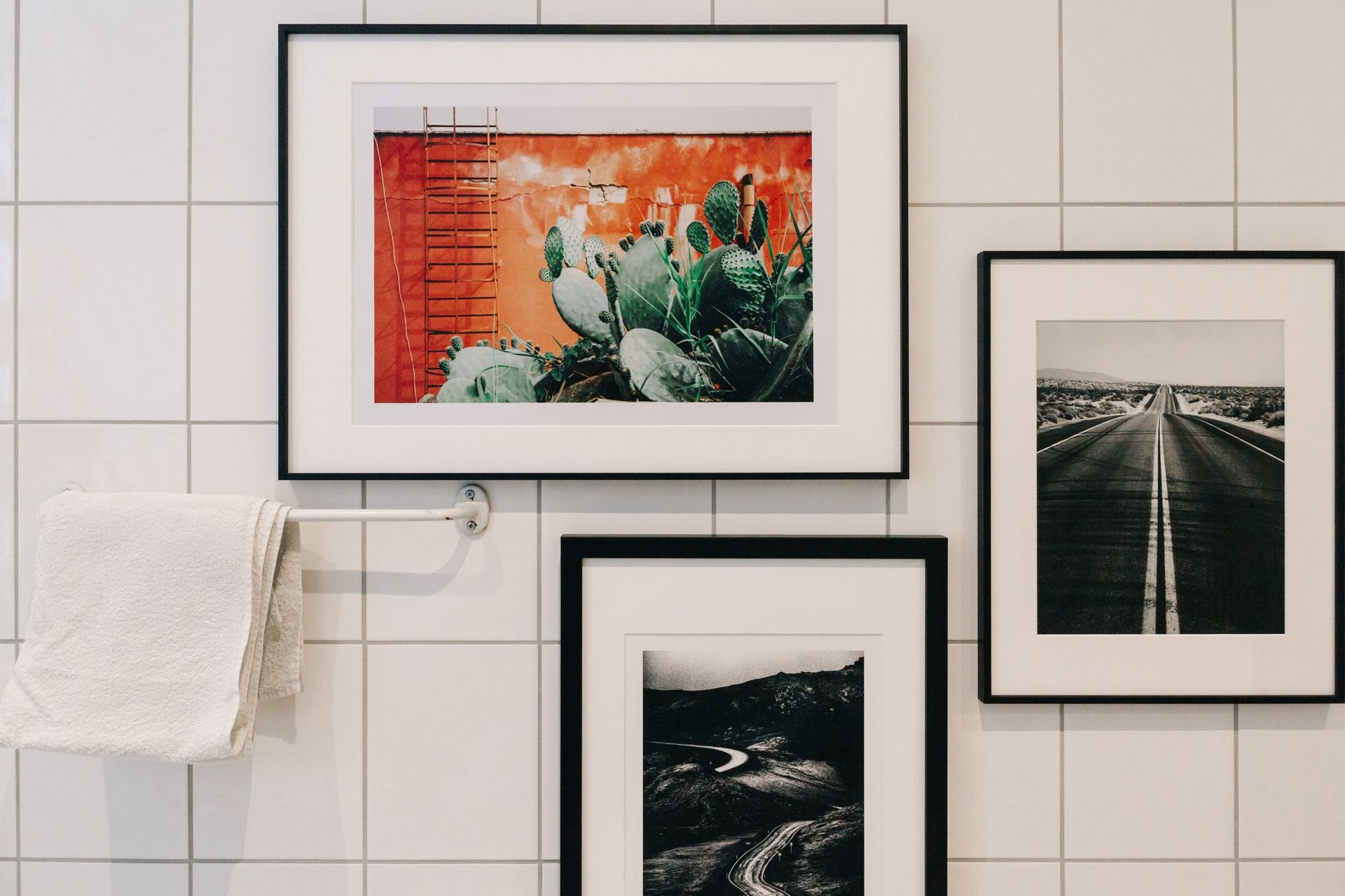 Framed art prints on a tiled wall above a white towel rack Framed art prints on a tiled wall above a white towel rack