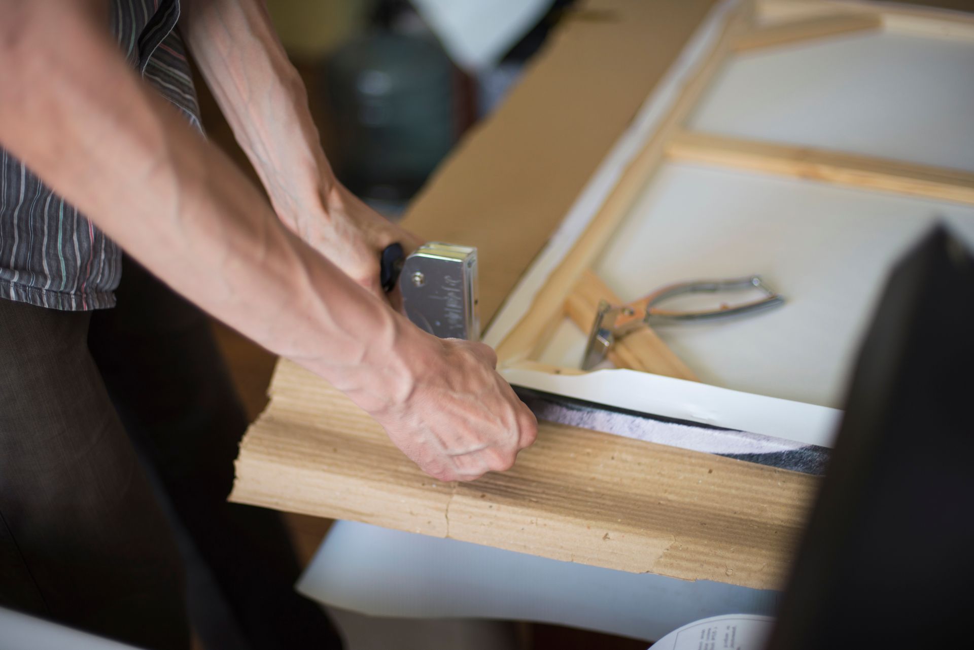 Stretching canvas over a wooden frame with a canvas stretching tool. Stretching canvas over a wooden frame with a canvas stretching tool.