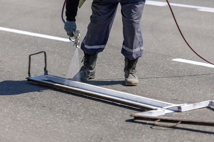 person spraying white lines on parking lot asphalt