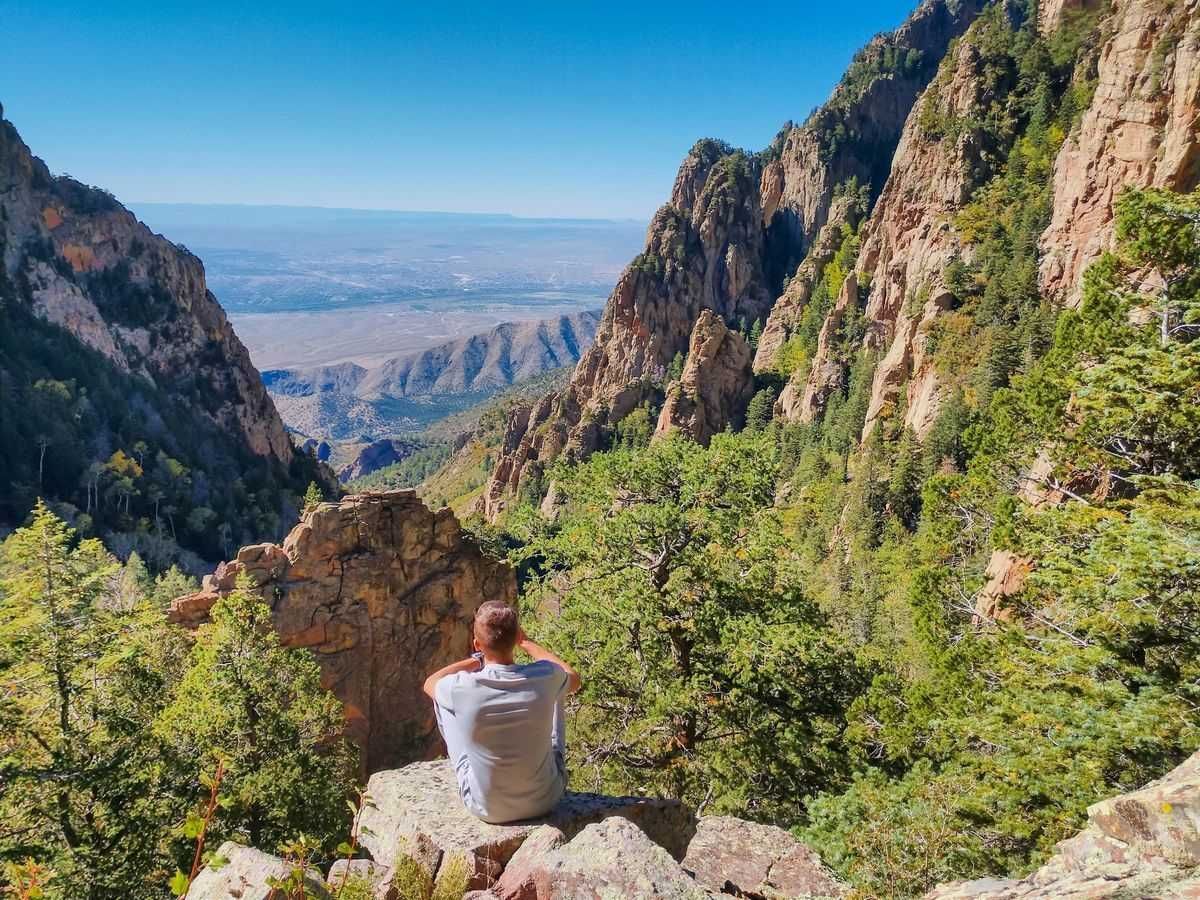 Man sitting quietly overlooking the Sandia Mountains in New Mexico, symbolizing mindfulness and meditation.