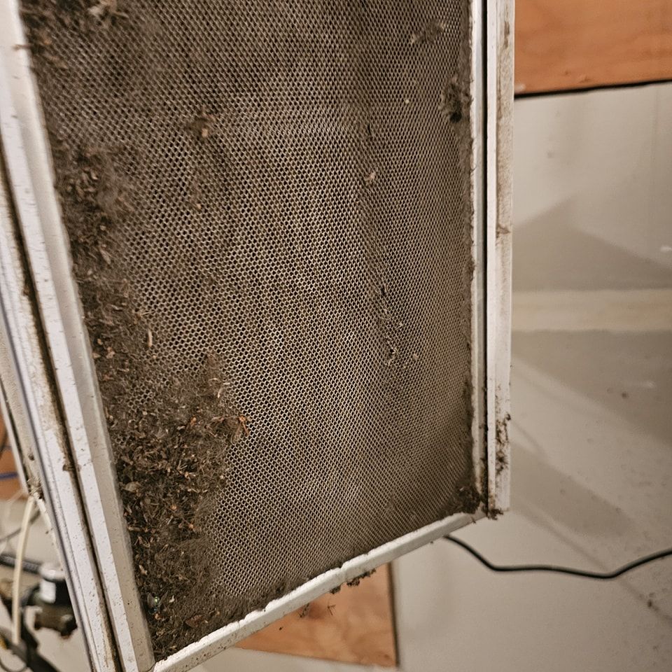 A dirty air filter is sitting on the floor in a room.