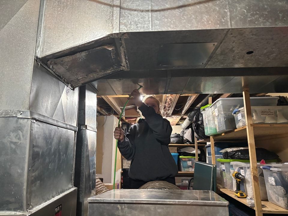 A man is working on a ventilation system in a garage.