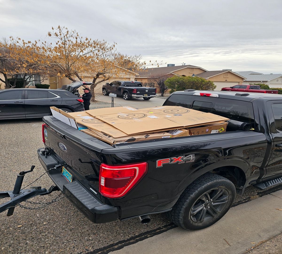 Black pickup truck with plywood sheets in the bed parked in a lot on an overcast day