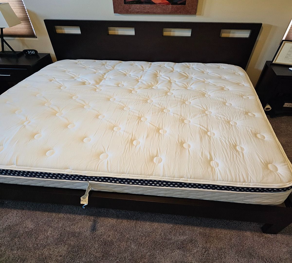 White mattress on a dark wood bed frame in a bedroom, with a headboard and carpeted floor