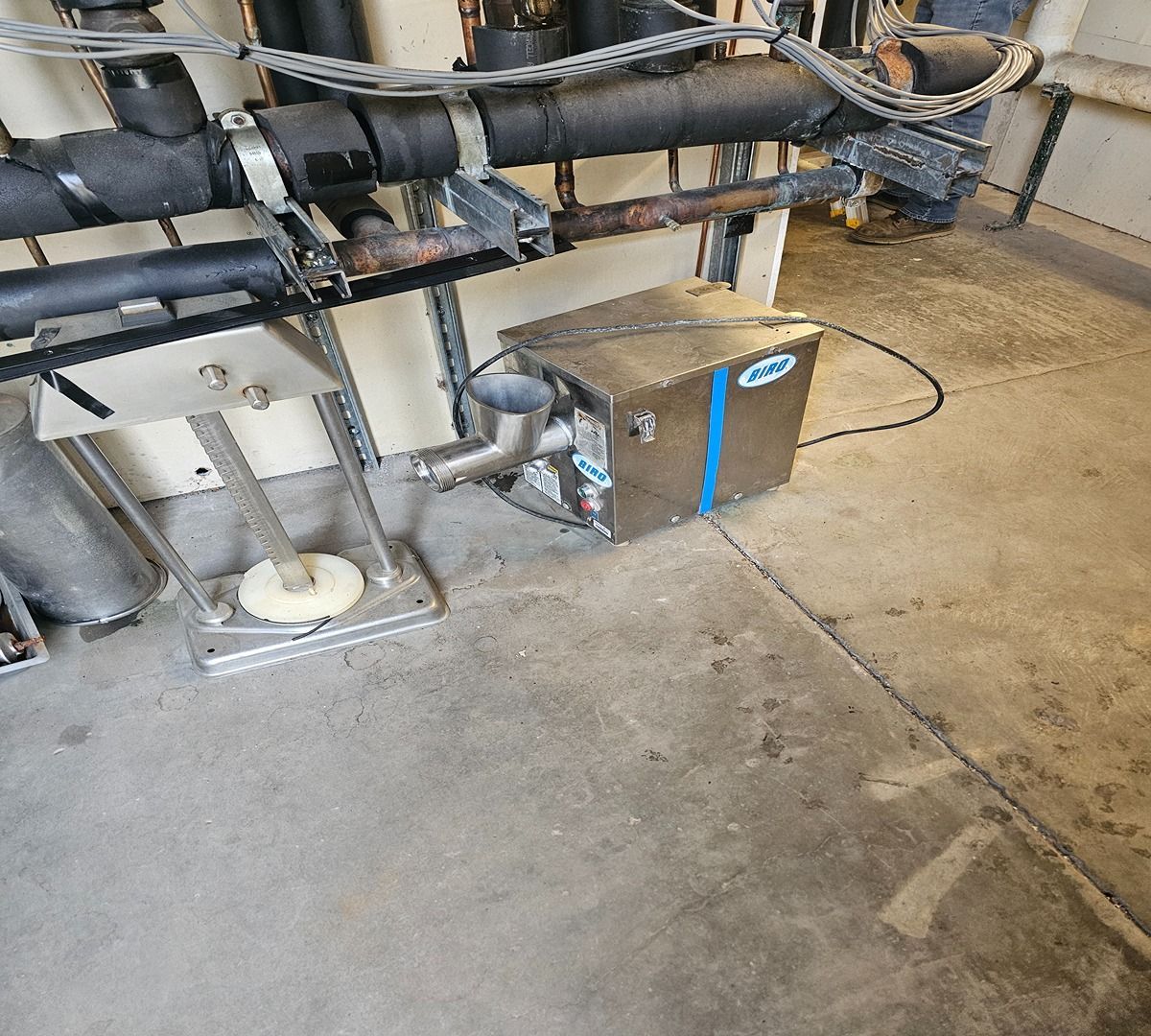 Industrial piping and equipment on a concrete floor in a utility room