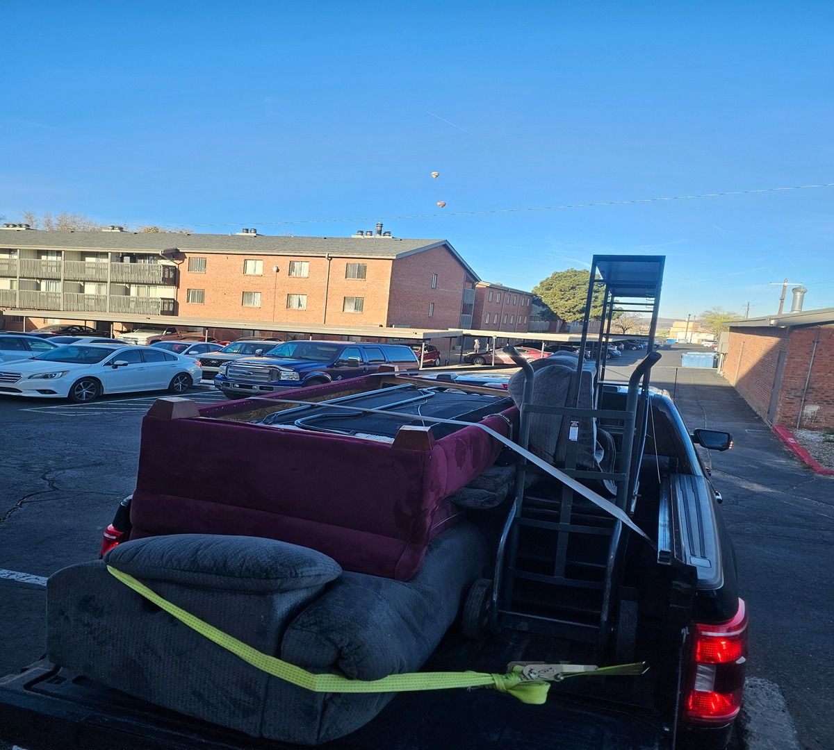 Pickup truck loaded with furniture and ladder in a parking lot beside apartment buildings