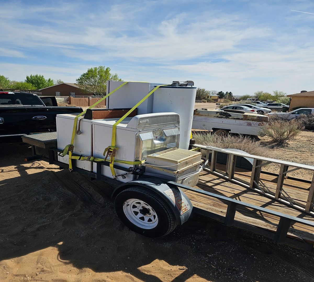 White machine strapped to a utility trailer in a desert lot under a blue sky