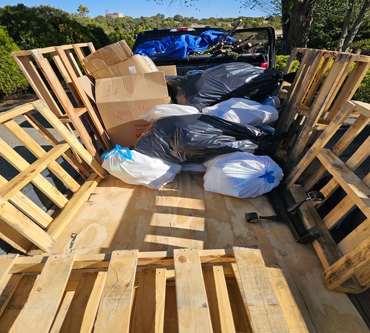 Open truck bed loaded with cardboard boxes and plastic bags, viewed from the rear.