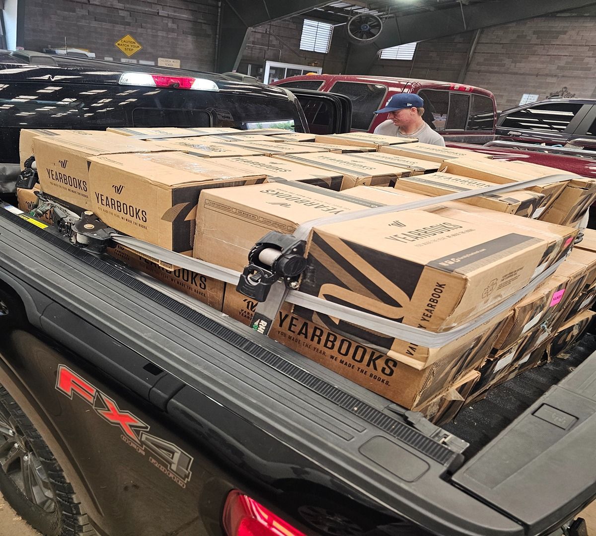 Pickup truck bed loaded with stacked cardboard boxes in a warehouse loading area
