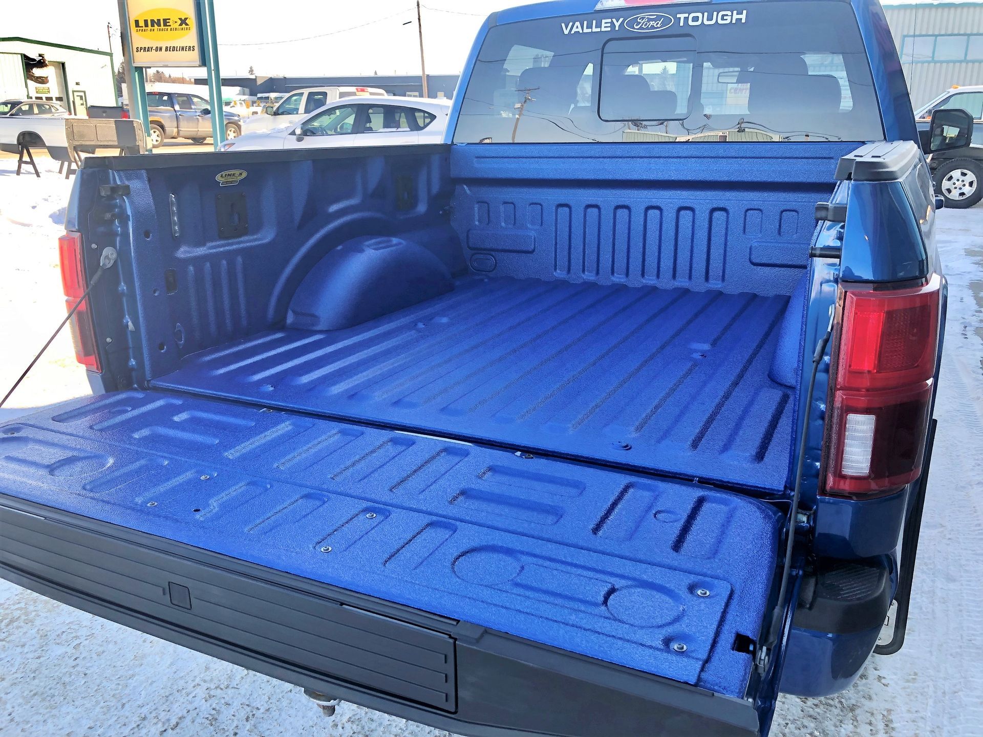 Blue pickup truck bed with a fold-down tailgate and open cargo area behind the cab