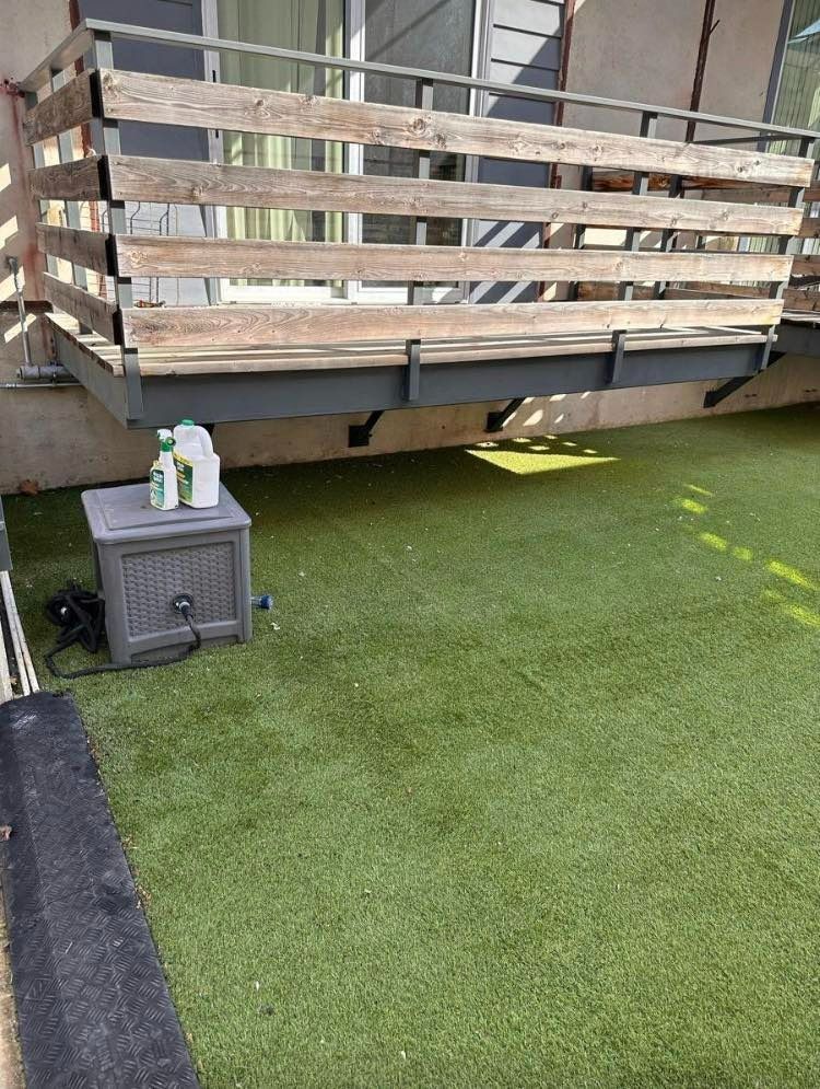Green artificial turf balcony with a wooden railing and a storage box.