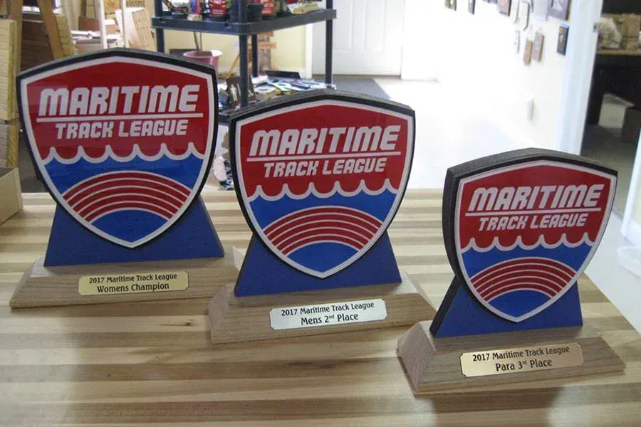 Three maritime track league trophies are sitting on a wooden table