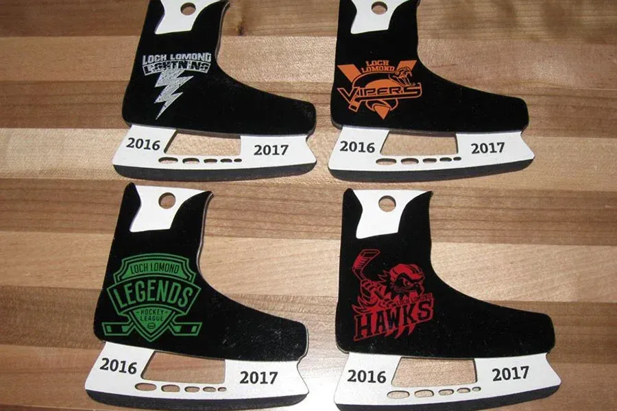 Four pairs of ice skates are sitting on a wooden table