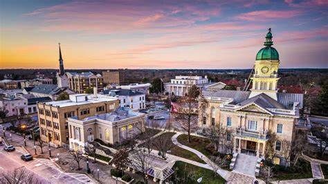 Downtown Athens, Georgia, with historic buildings, a clock tower, and a colorful sunset sky.