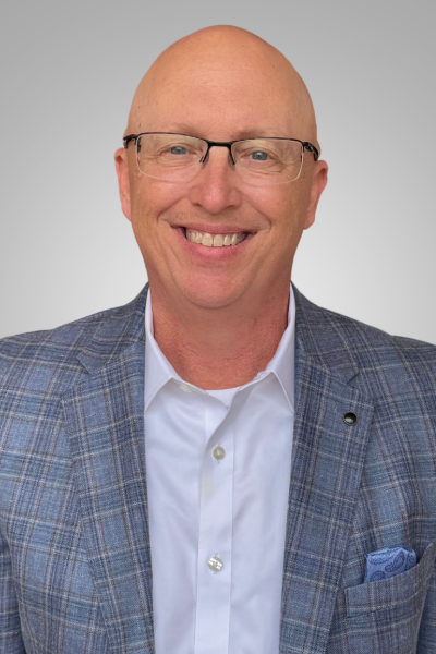 Bald man smiling, wearing glasses, blue plaid blazer, and white shirt.