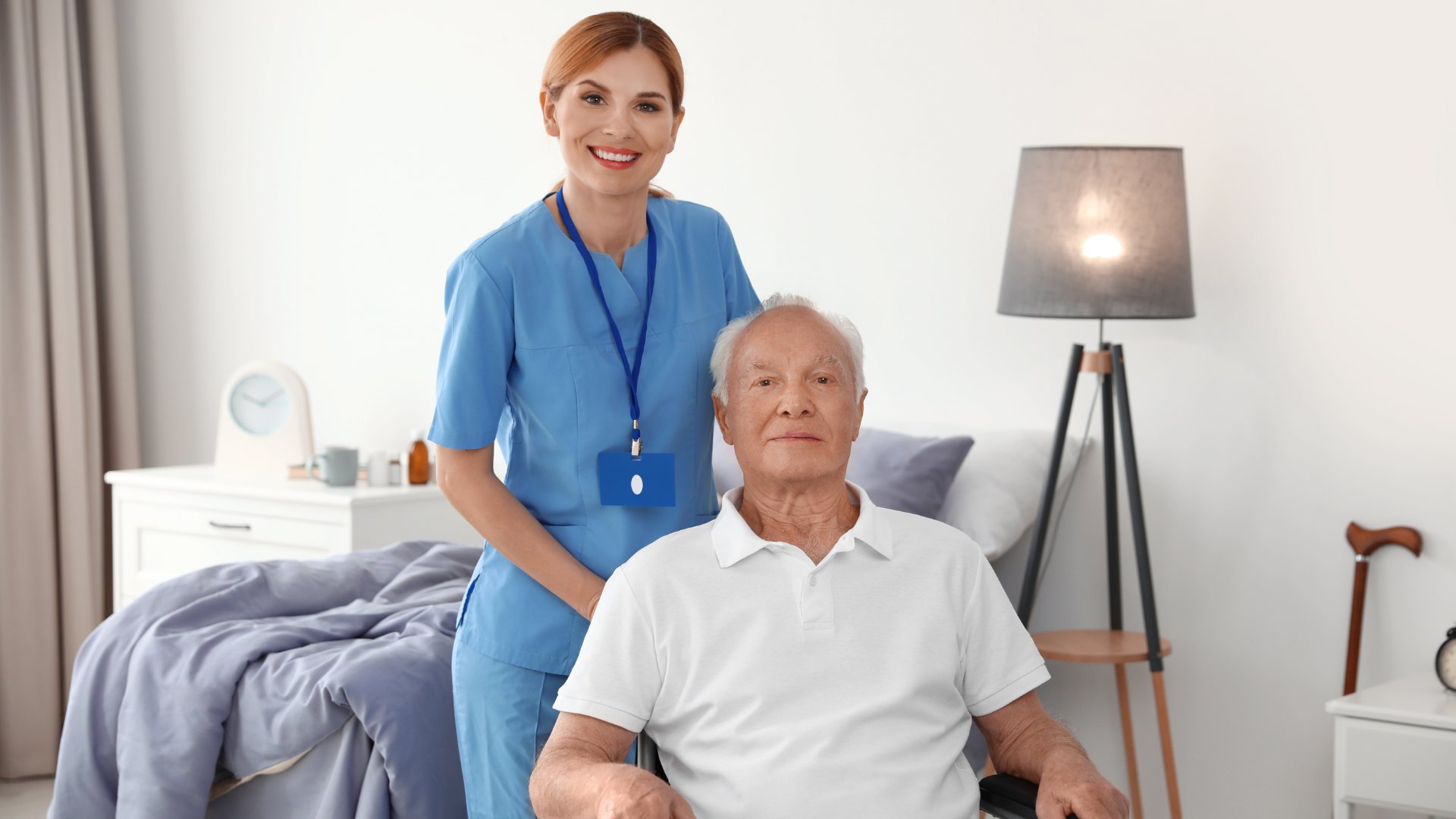 A nurse is standing next to an elderly man in a wheelchair.
