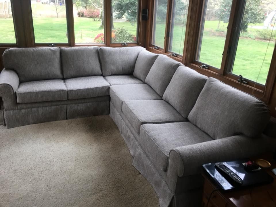 Gray sectional sofa in a sunroom with large windows and a carpeted floor