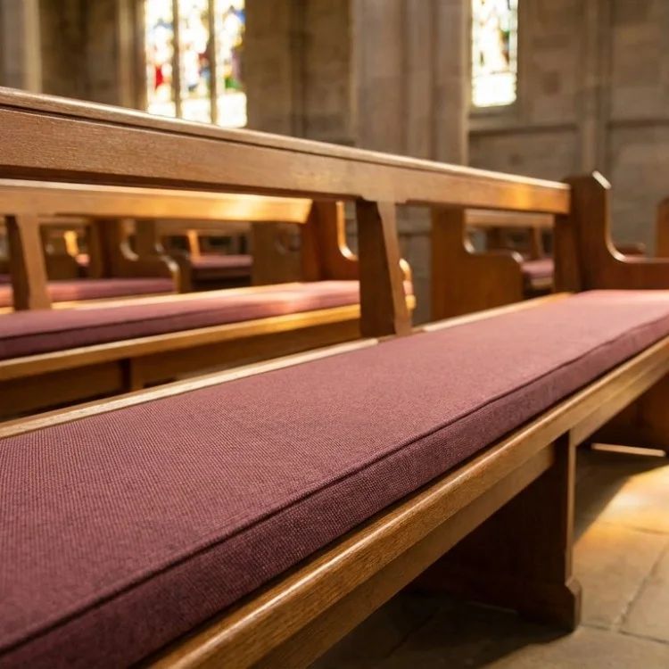 Wooden church pews with purple cushions in a sunlit sanctuary