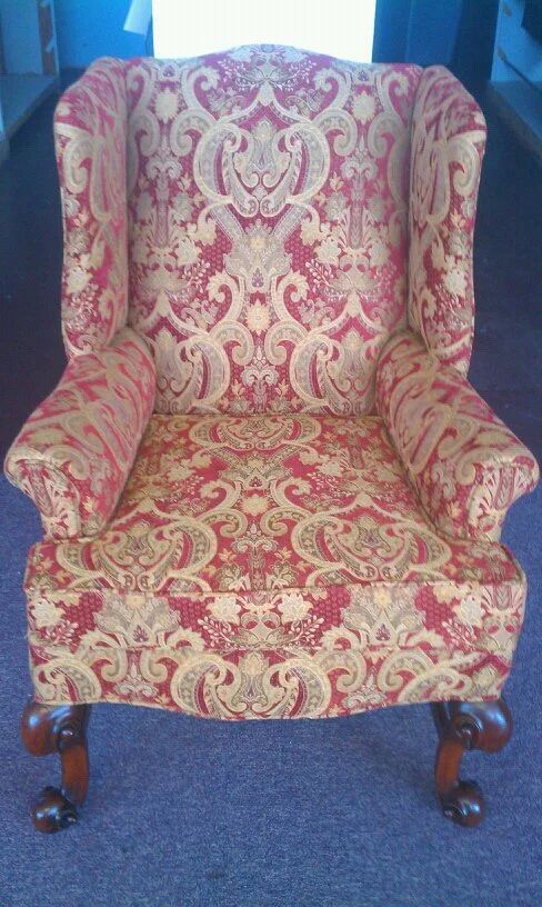 Ornate red and gold upholstered armchair with carved wooden legs on a blue carpet