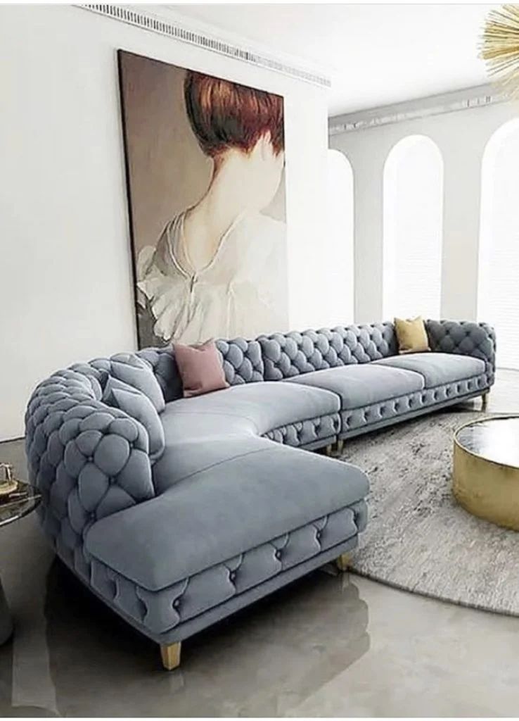 Modern living room with a gray tufted sectional sofa, large portrait art, and a round coffee table